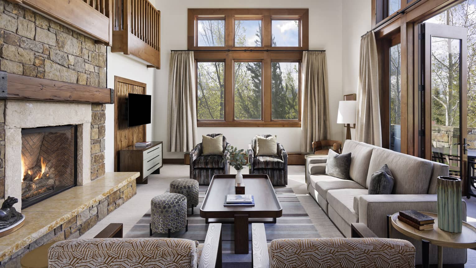 Living room with sofa and four arm chairs, stone fire place, open loft
