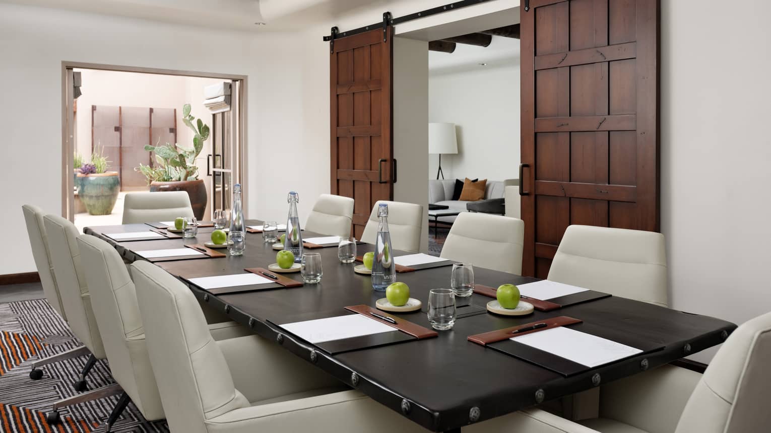 A meeting rom with leather chairs around a large rectangular table, two large wooden sliding door are on a wall.