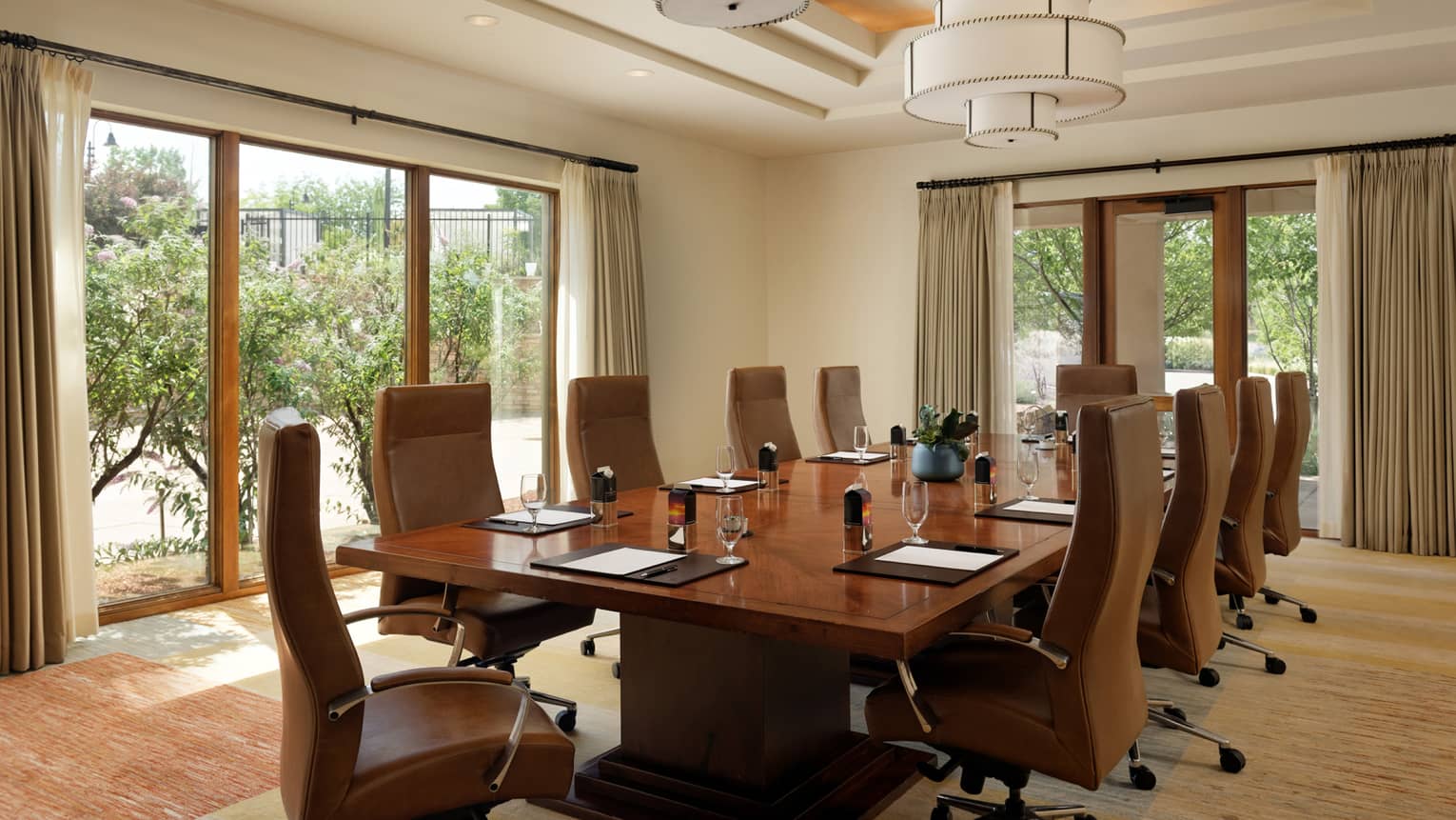 Meeting room with brown tables and rolling chairs and floor-to-ceiling windows.