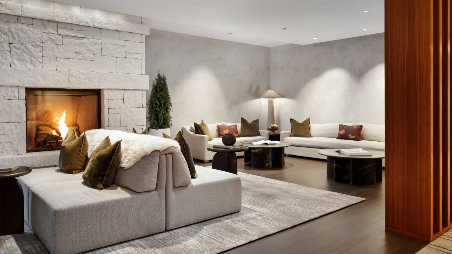 Spa relaxation area with cream couches, in-wall stone fireplace and dark wood floors
