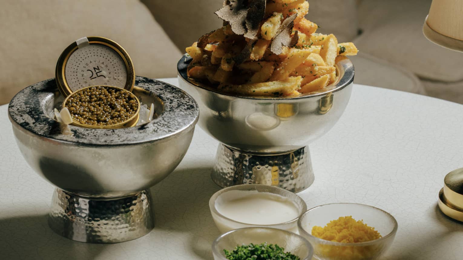  Caviar served on ice along with small bowls of goug�res, egg yolk, cr�me fra�che chives, and a silver bowl of French fries