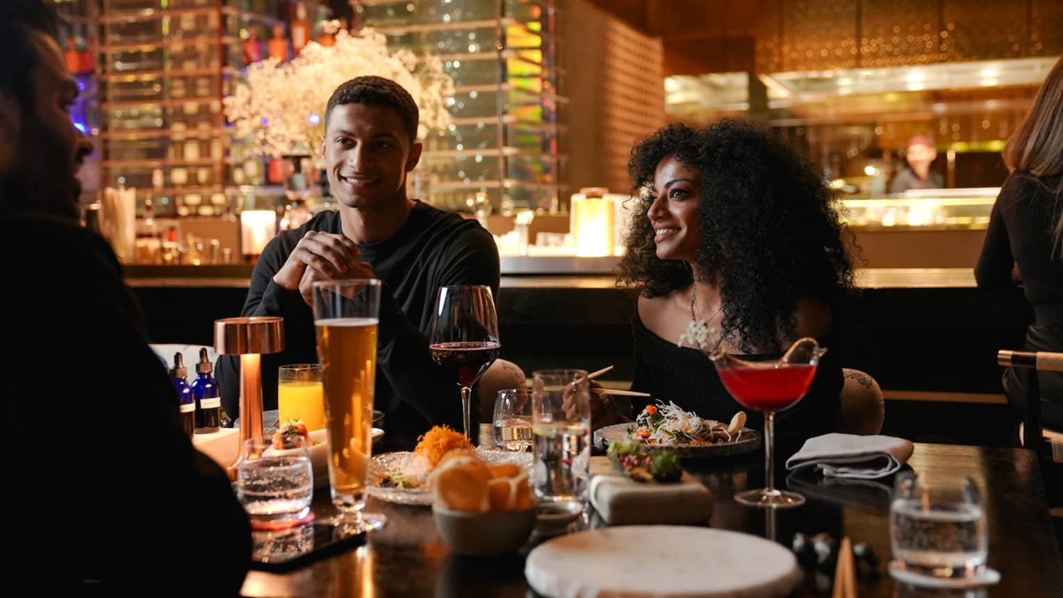Group of people sit at a dining table with an open kitchen behind them