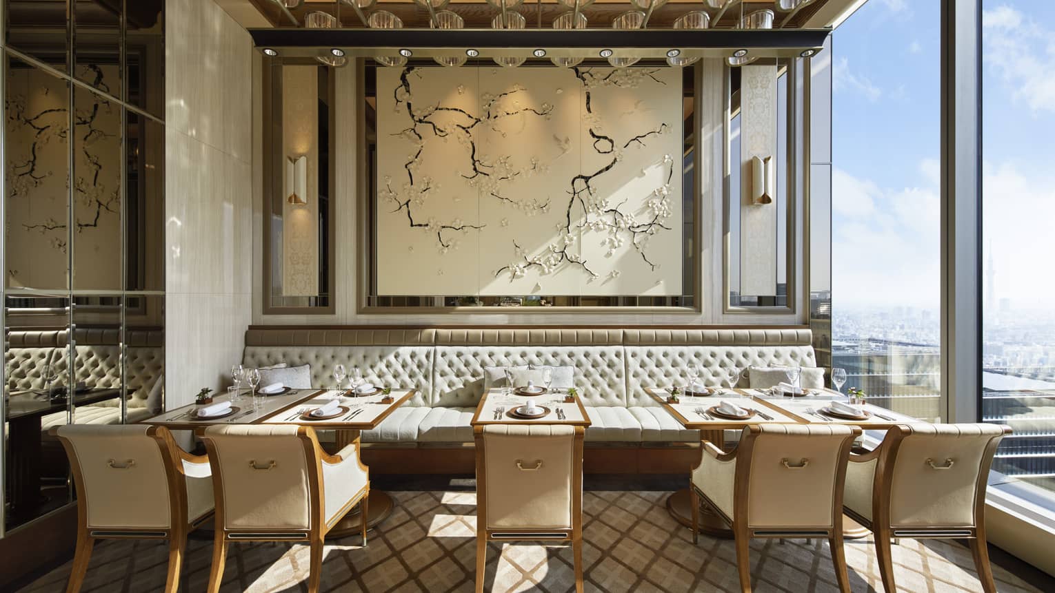 Est dining room with tables for two, muted cream decor, natural light, view of the city 