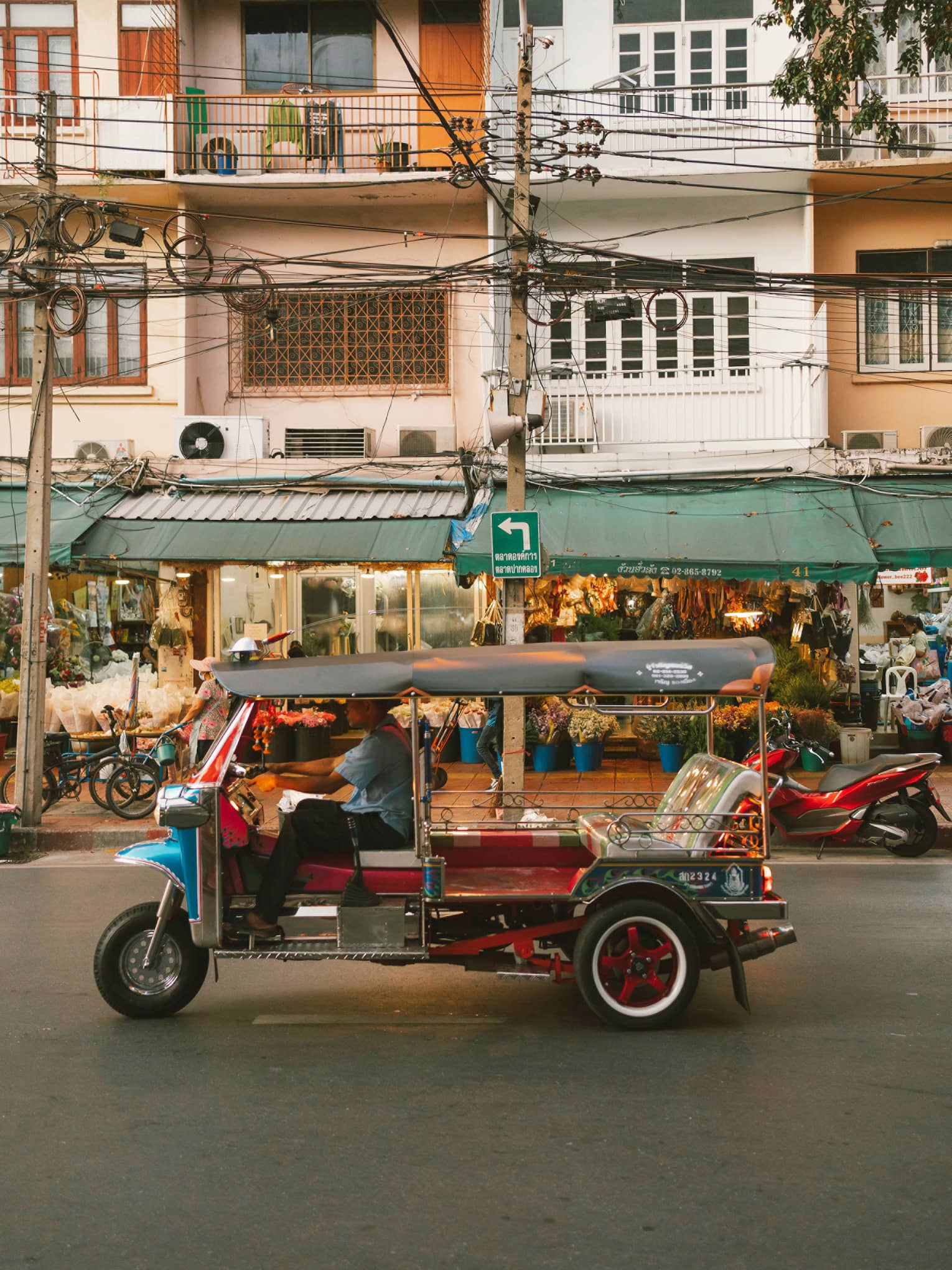 Colourful auto rickshaw parked in front of three-storey building with green awning