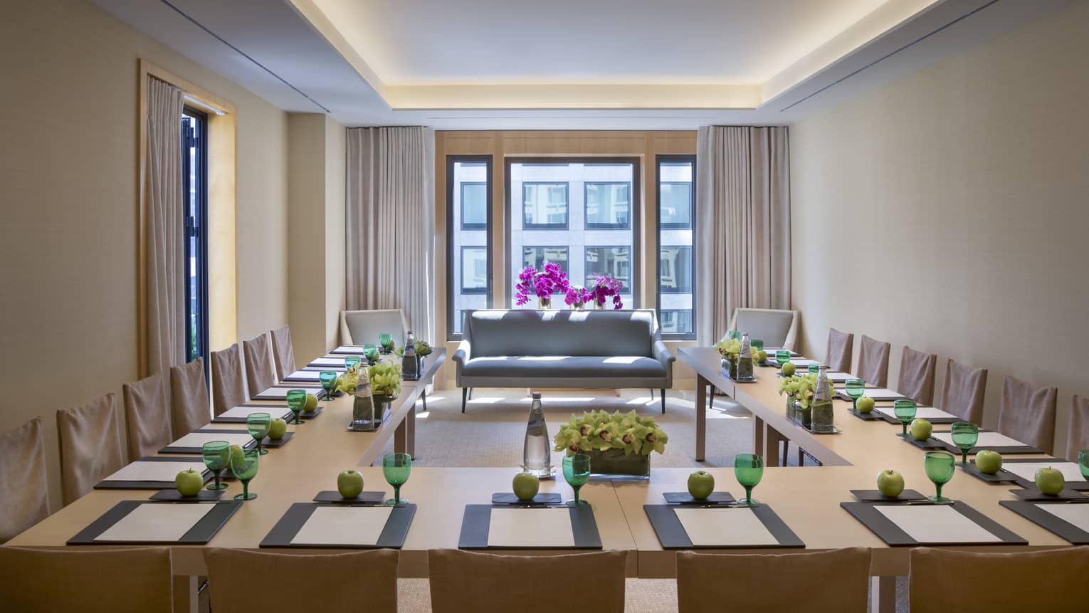 Modular conference table around small vintage-style sofa and orchids by sunny window