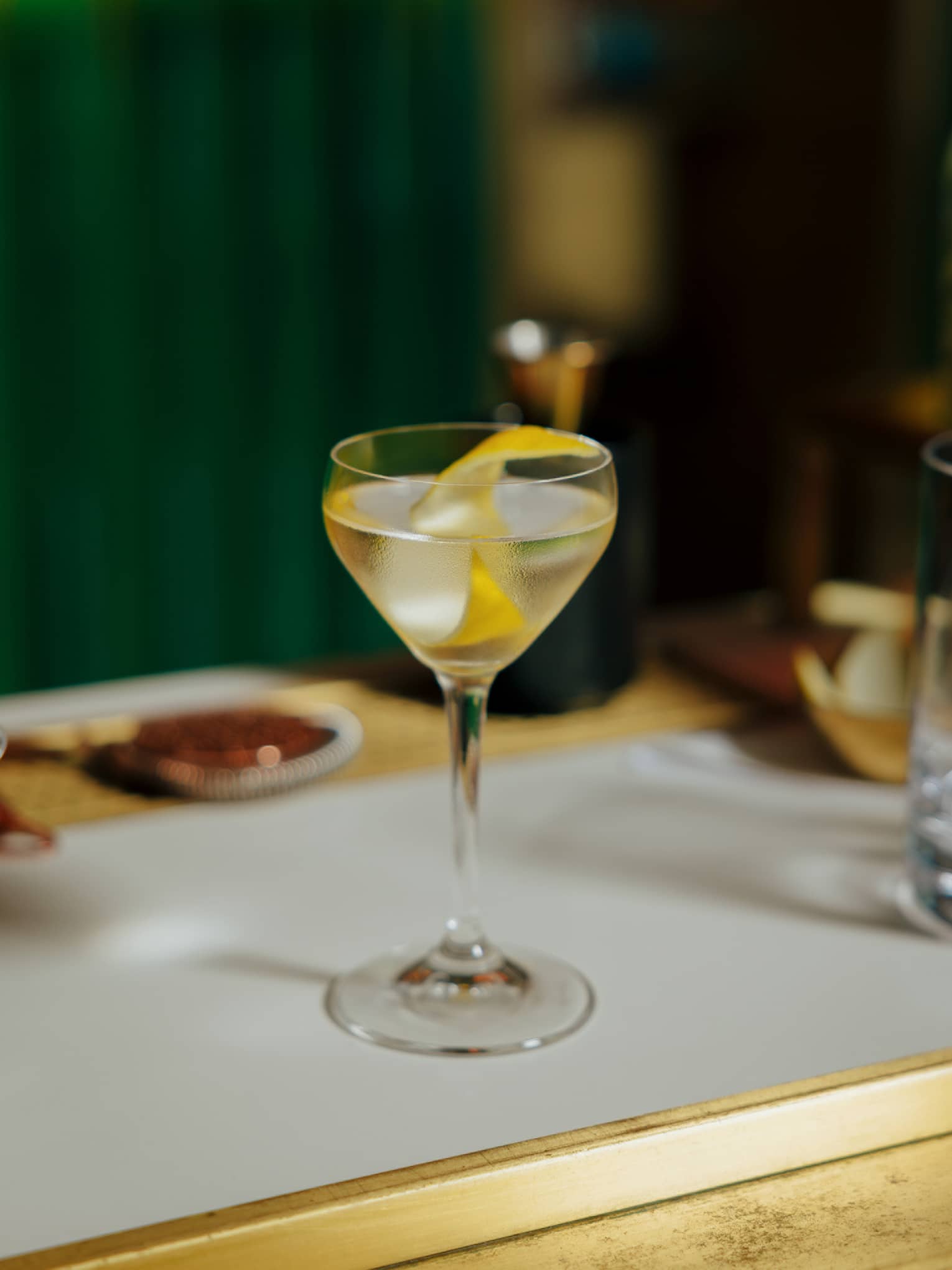 Cocktail in a stemmed glass garnished with a slice of lemon peel