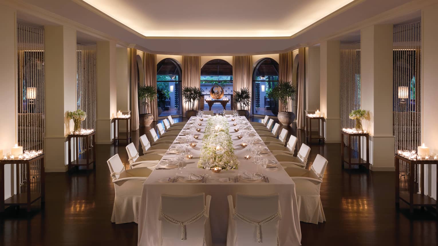 Long banquet wedding dining table with white floral centrepiece, tea lights in small copper bowls