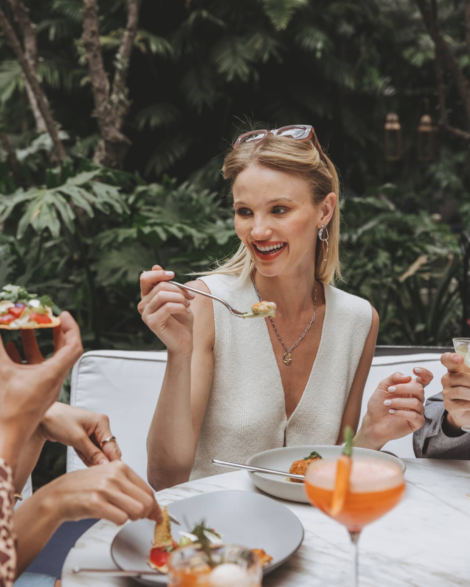 A woman enjoys food and a cocktail outdoors