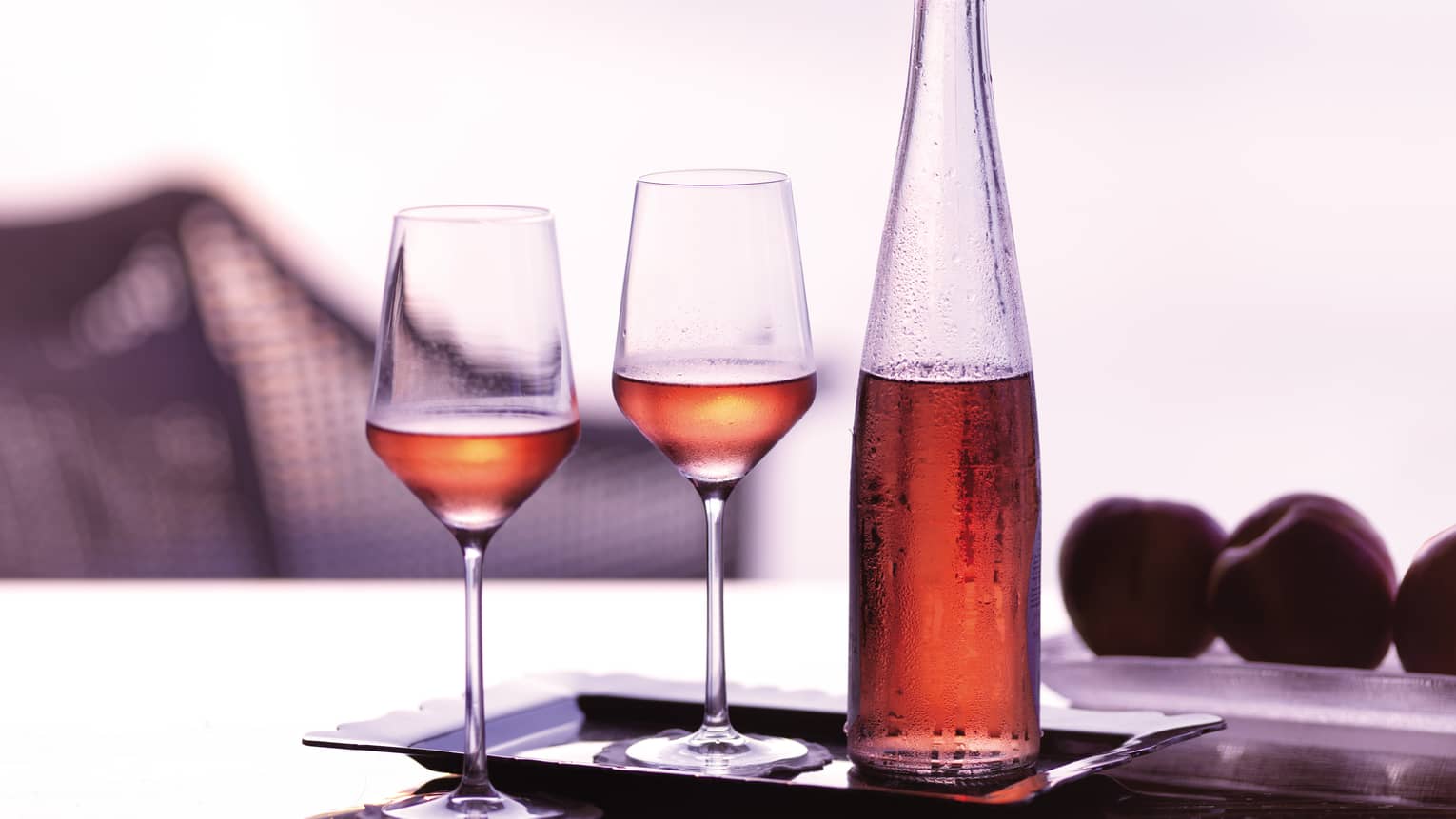 Tray with two wine glasses and glass bottle with rosee 