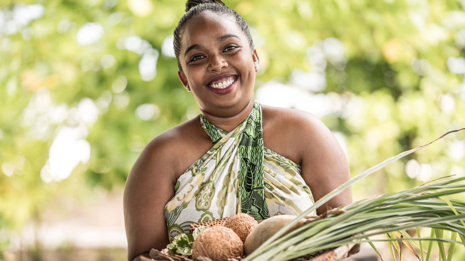 Smiling woman holds spa basket with coconuts, lemongrass, herbs