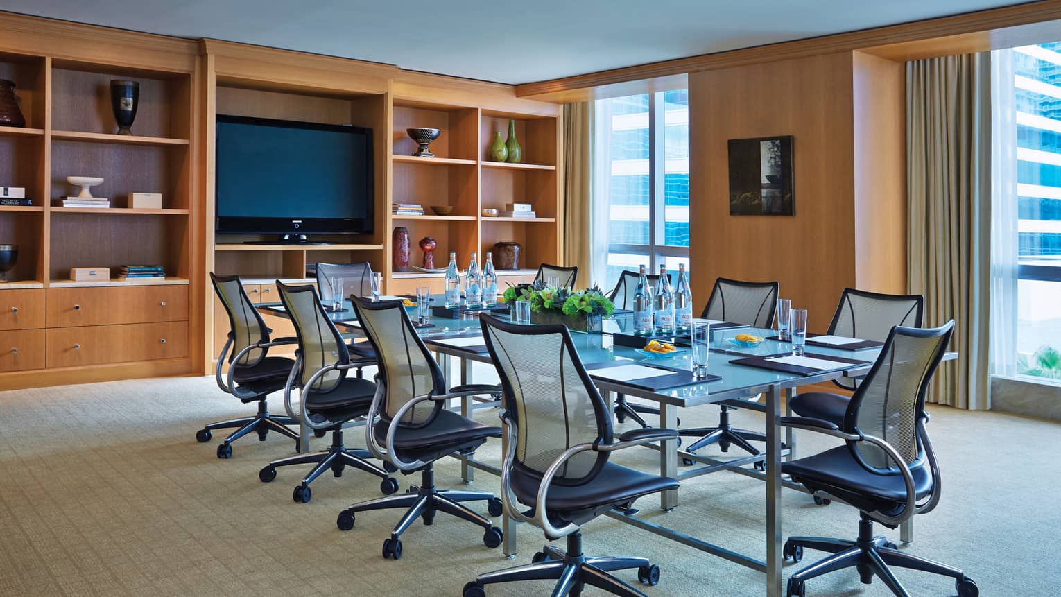 Swivel chairs line boardroom table in bright meeting room with shelves