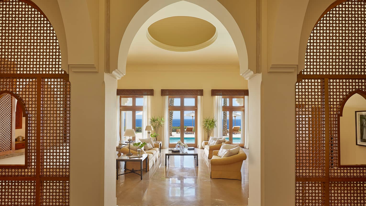 Royal Suite sunny living room under soaring ceiling past decorative wood screens