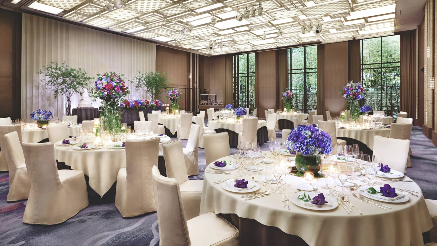 Ballroom event with round banquet tables under patterned, panel ceiling, lights