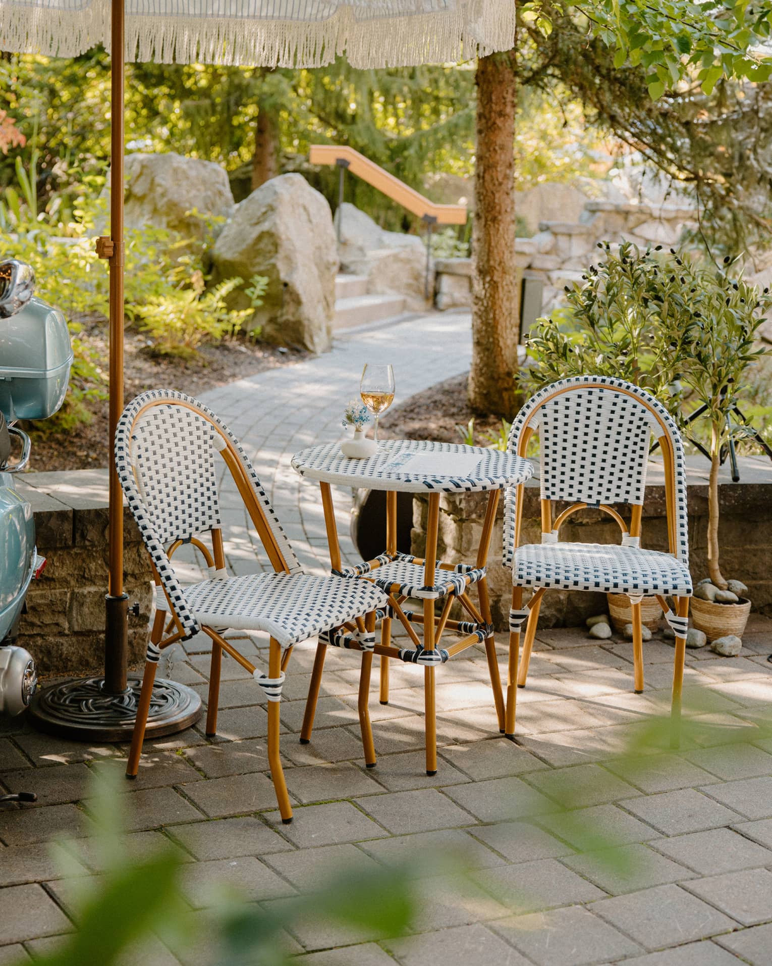 Two polka-dotted chairs and matching two-seater table on stone patio with walkway leading to steps