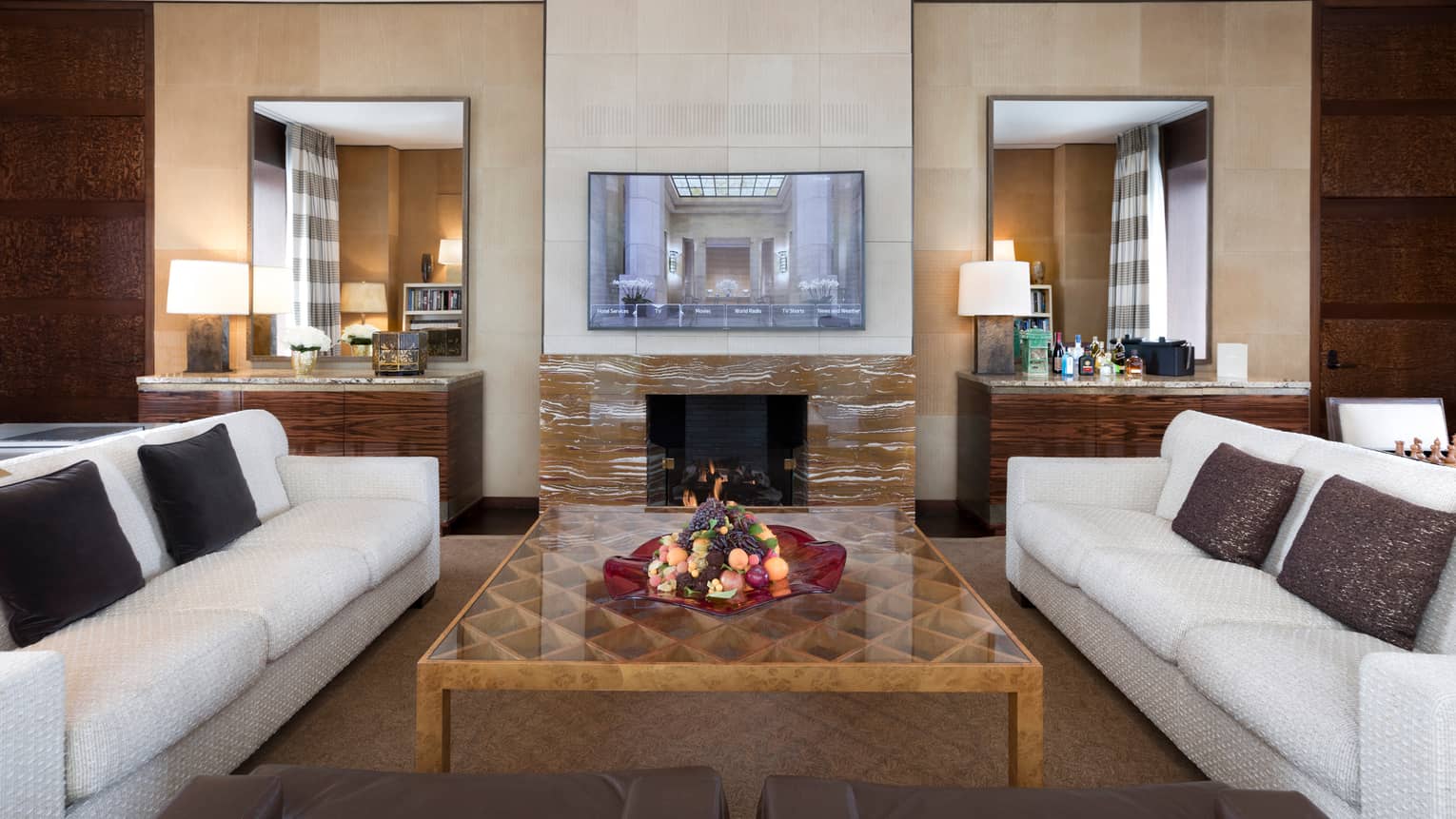 Presidential Suite white sofas around large table, wood-grain marble fireplace, TV on mantle
