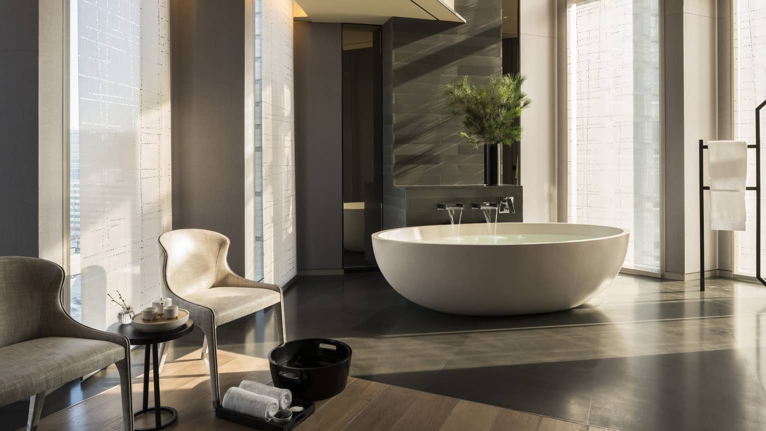 Water pouring into round white bath, two chairs, towels and foot bath at Sulwhasoo spa