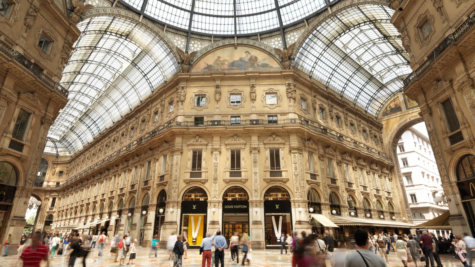 Shoppers gathered in  historic Galleria Vittorio Emanuele building with soaring ceilings, shops