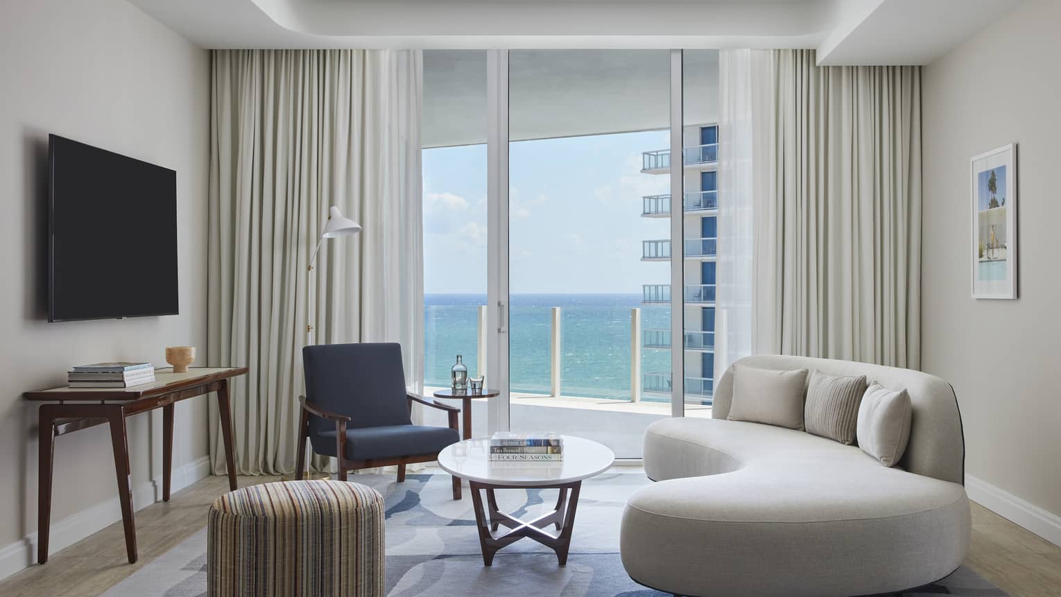 Living room with curved sofa, chair, table, ocean view