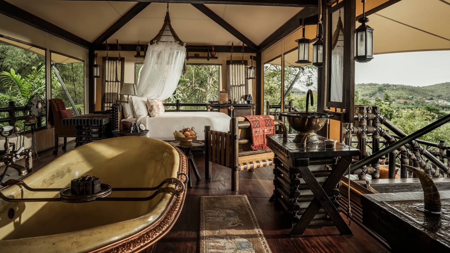 Outdoor open-air room with bed, tub, lanterns and mountain views