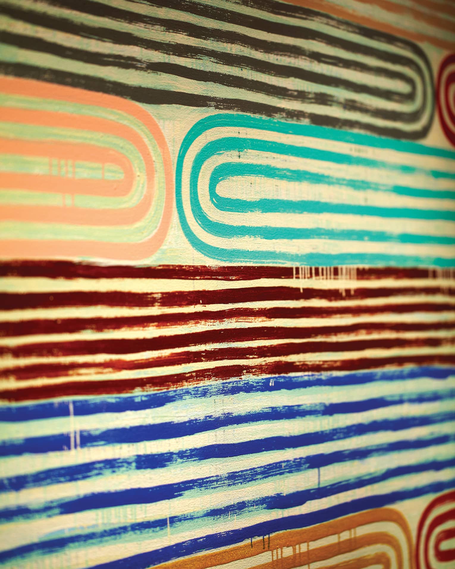 Close-up of pink, teal, red and blue lines of paint in pattern on canvas 