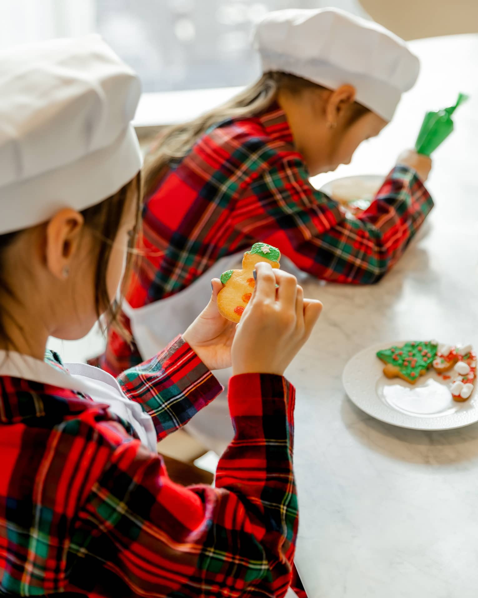 Two kids decorate holiday cookies