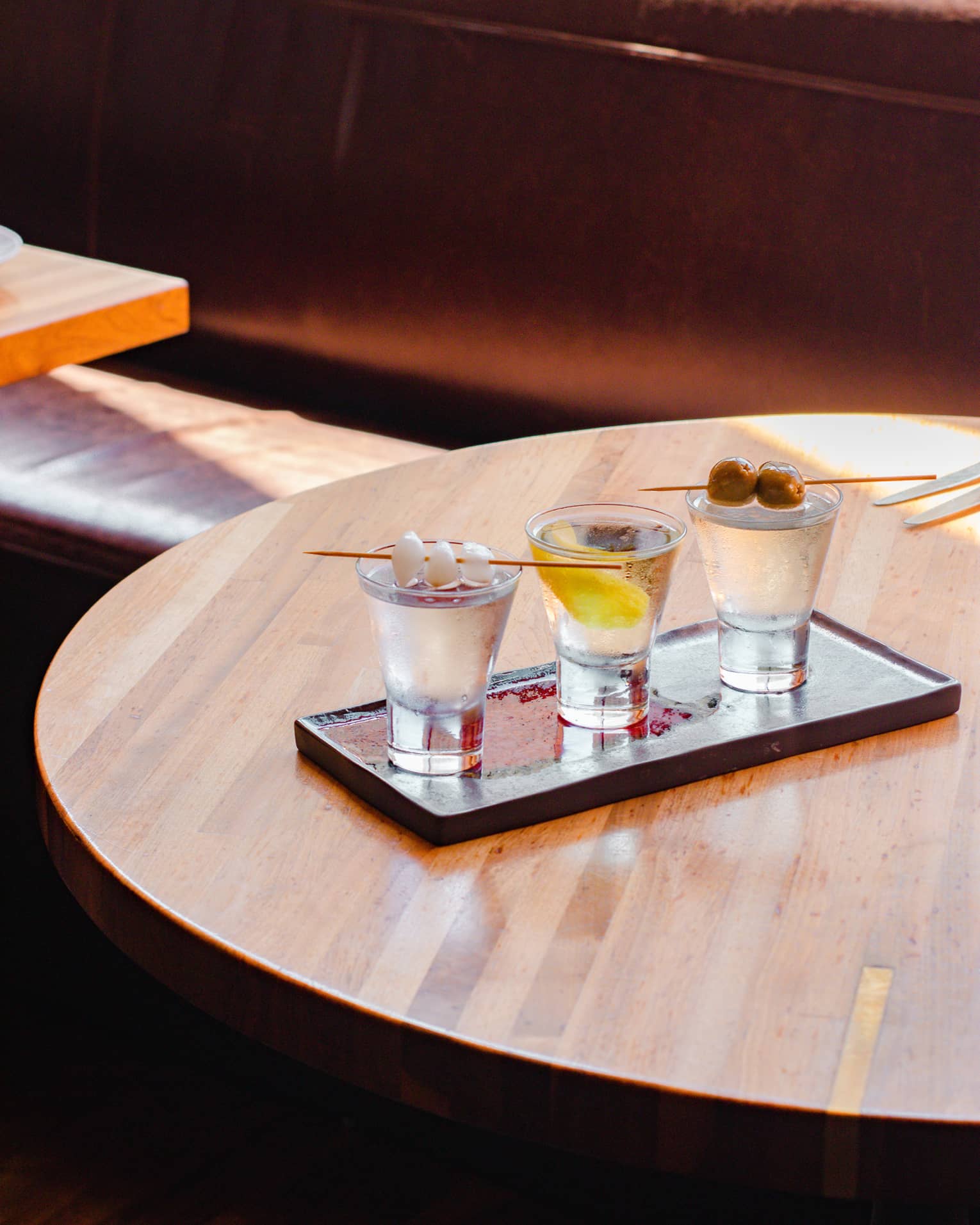 A flight of martinis on a wood table.