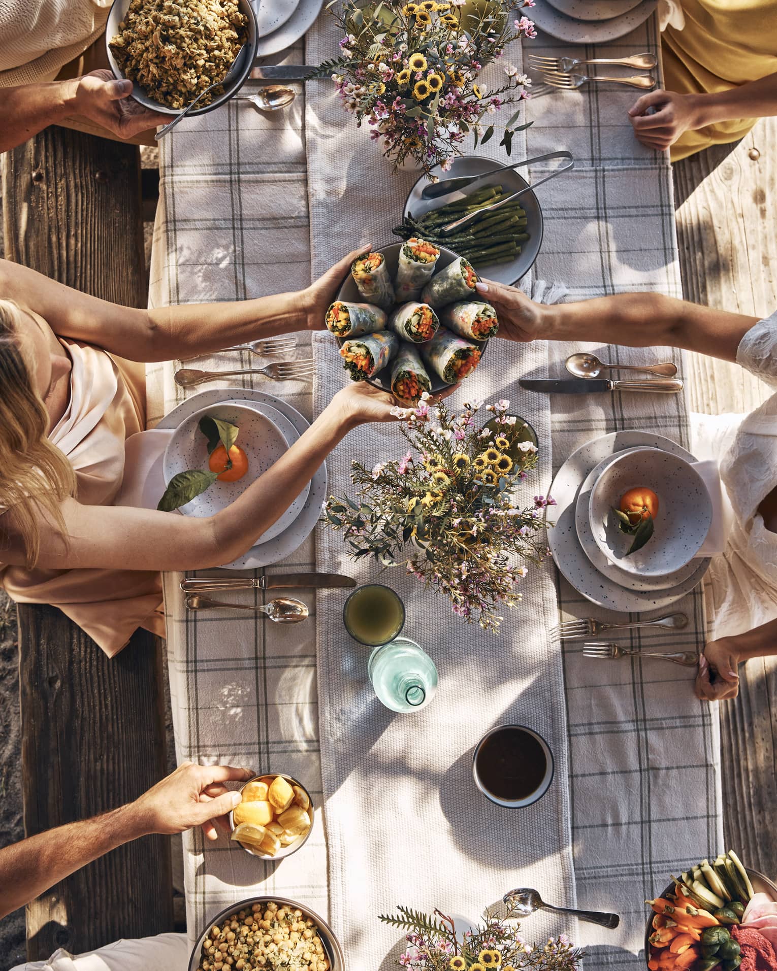 Guests sitting around a table and passing bowls of food.