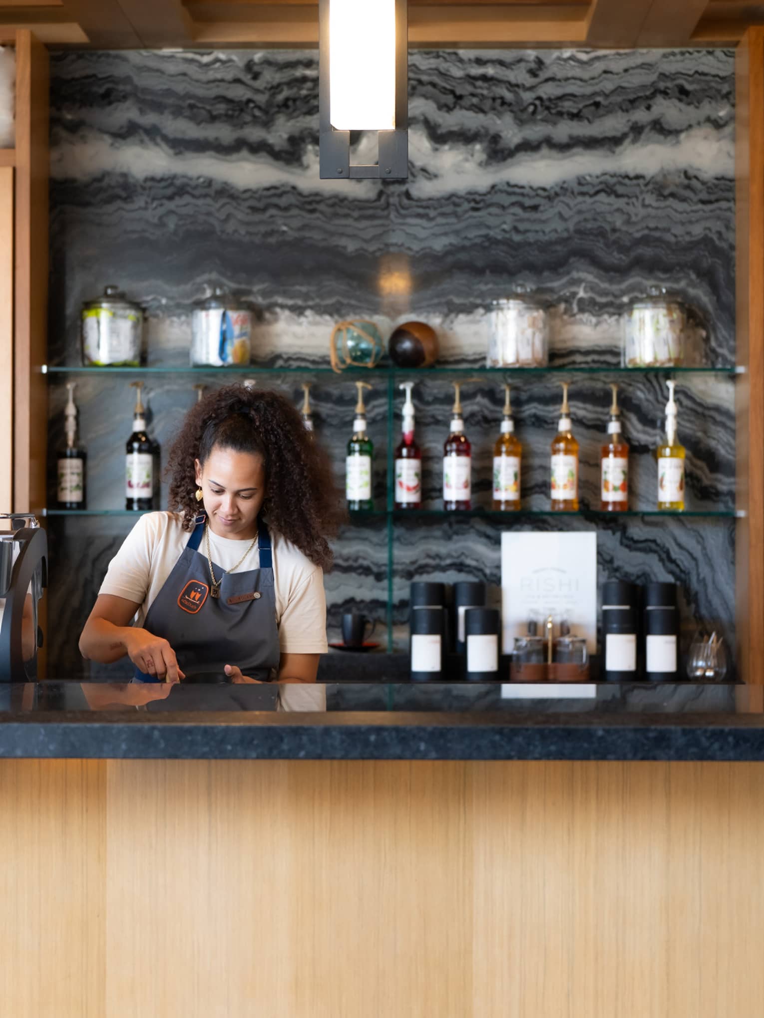 A woman wearing apron works behind a caf� counter