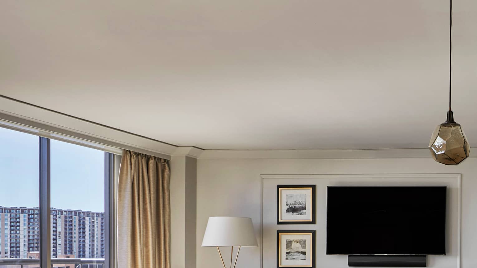 Governor's Suite white stools at tall wood table, three modern hanging lights, bright living room