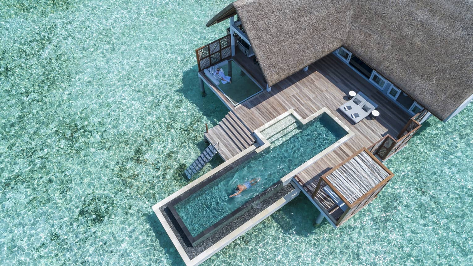 Aerial view of water villa with long swimming pool over lagoon