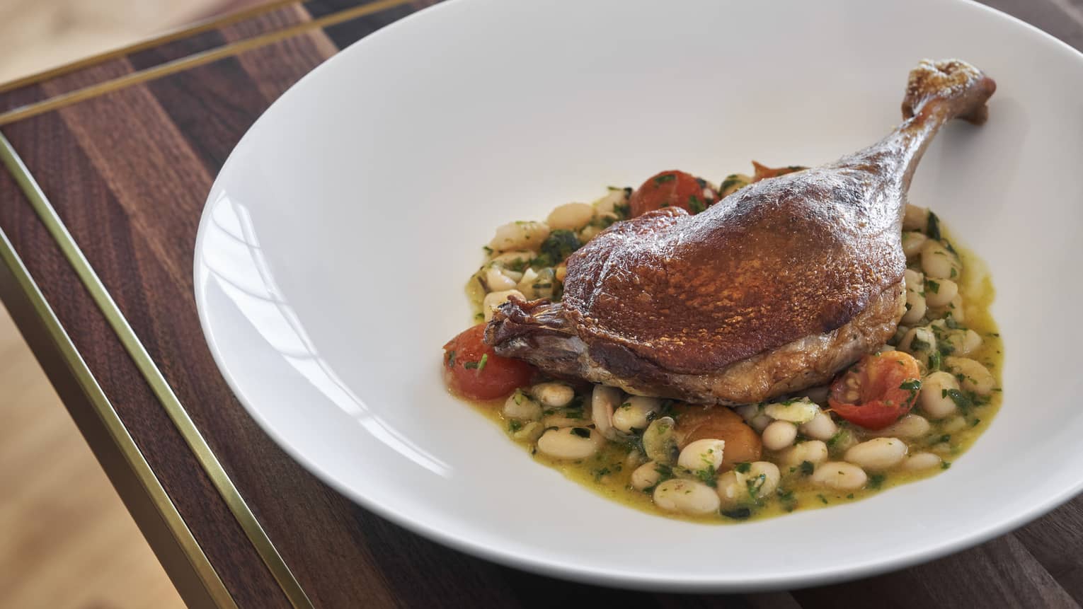 Cooked duck leg on a white plate.