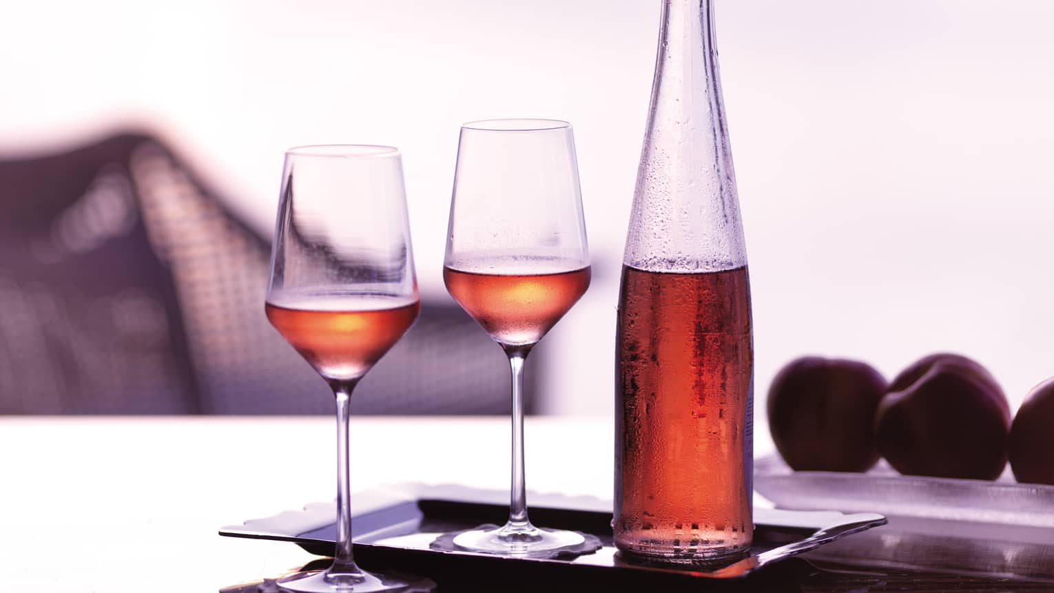 Tray with two wine glasses and glass bottle with rosee 