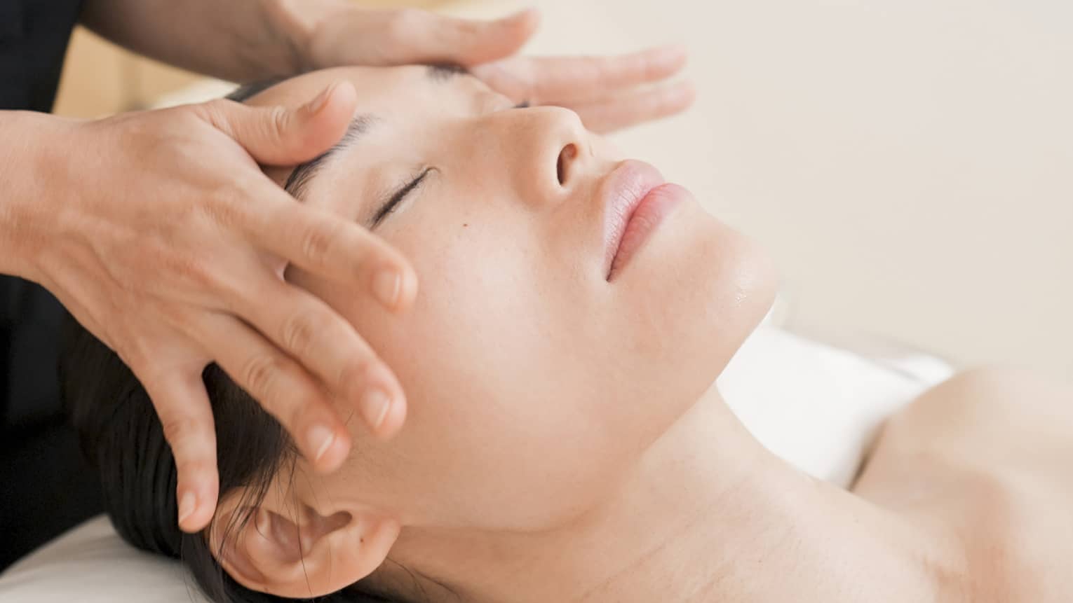 Person with eyes closed receiving head massage