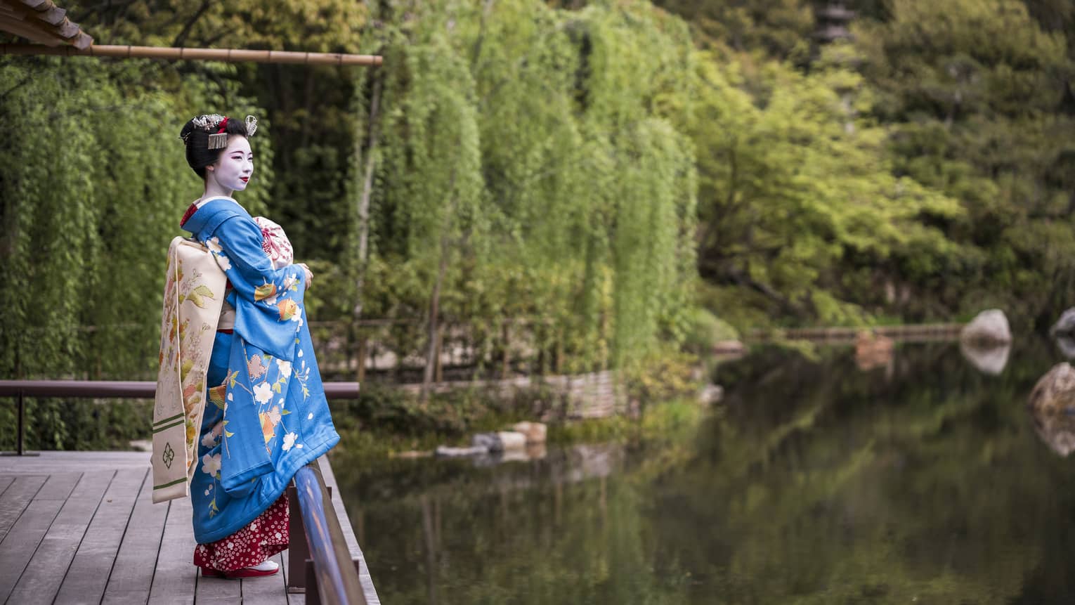 A geisha stands on the dock of the yoga barn and overlooks the serene lake