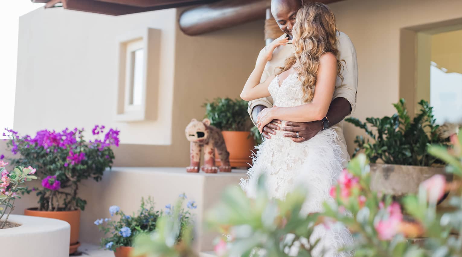 A bride and groom embrace each other on an outdoor terrace
