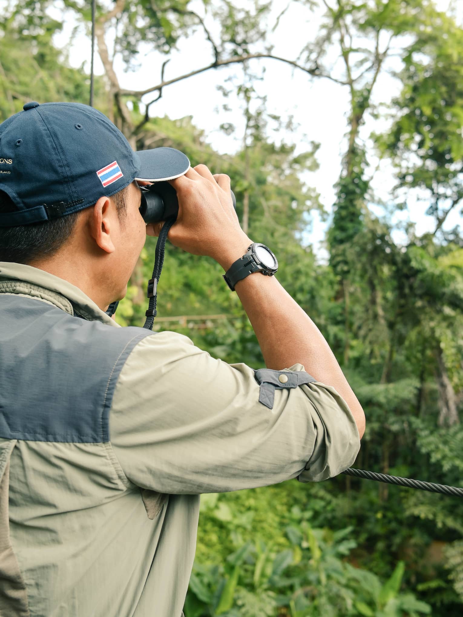 A man looks for birds through binoculars in jungle