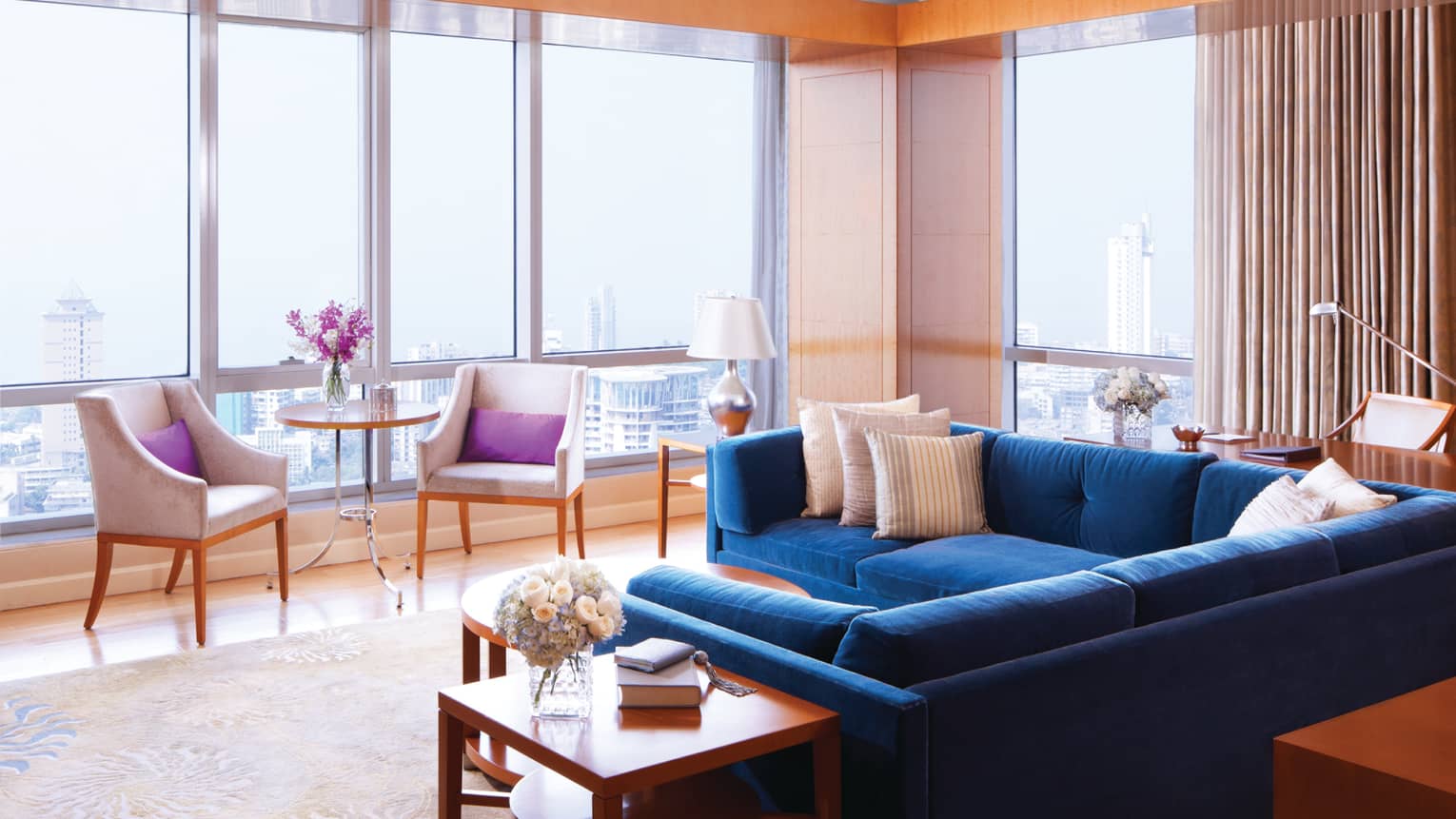 Deluxe Suite-Sea room with blue sectional sofa by floor-to-ceiling sunny windows, chairs