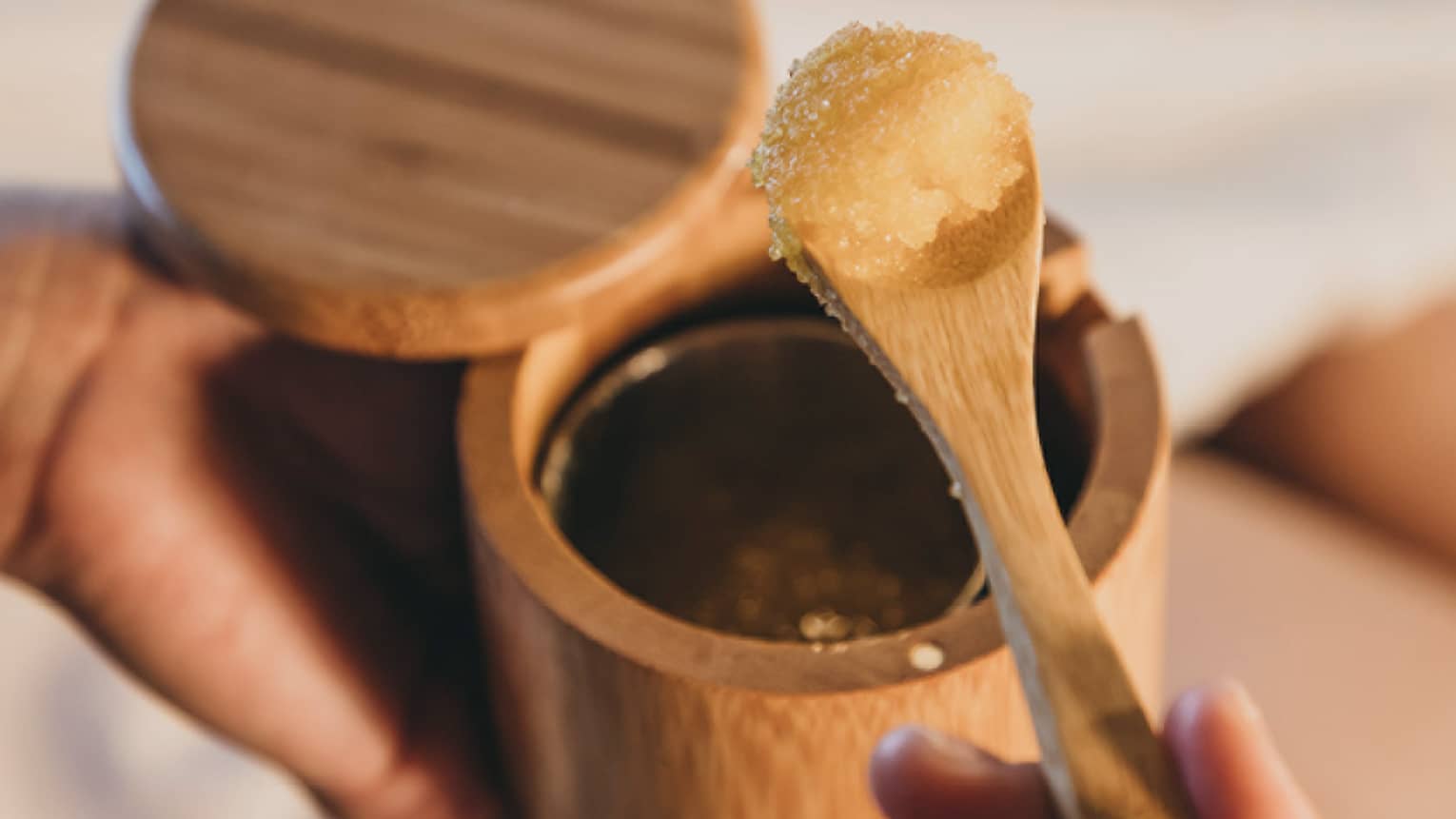A spa staff member scoops some sugar scrub out of a bamboo container in Hawaii