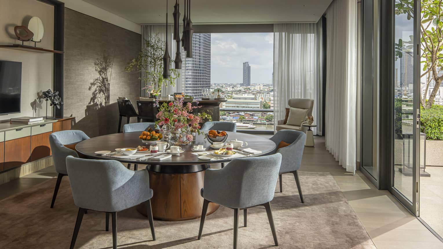 Hotel suite with large round dining table and views of Bangkok