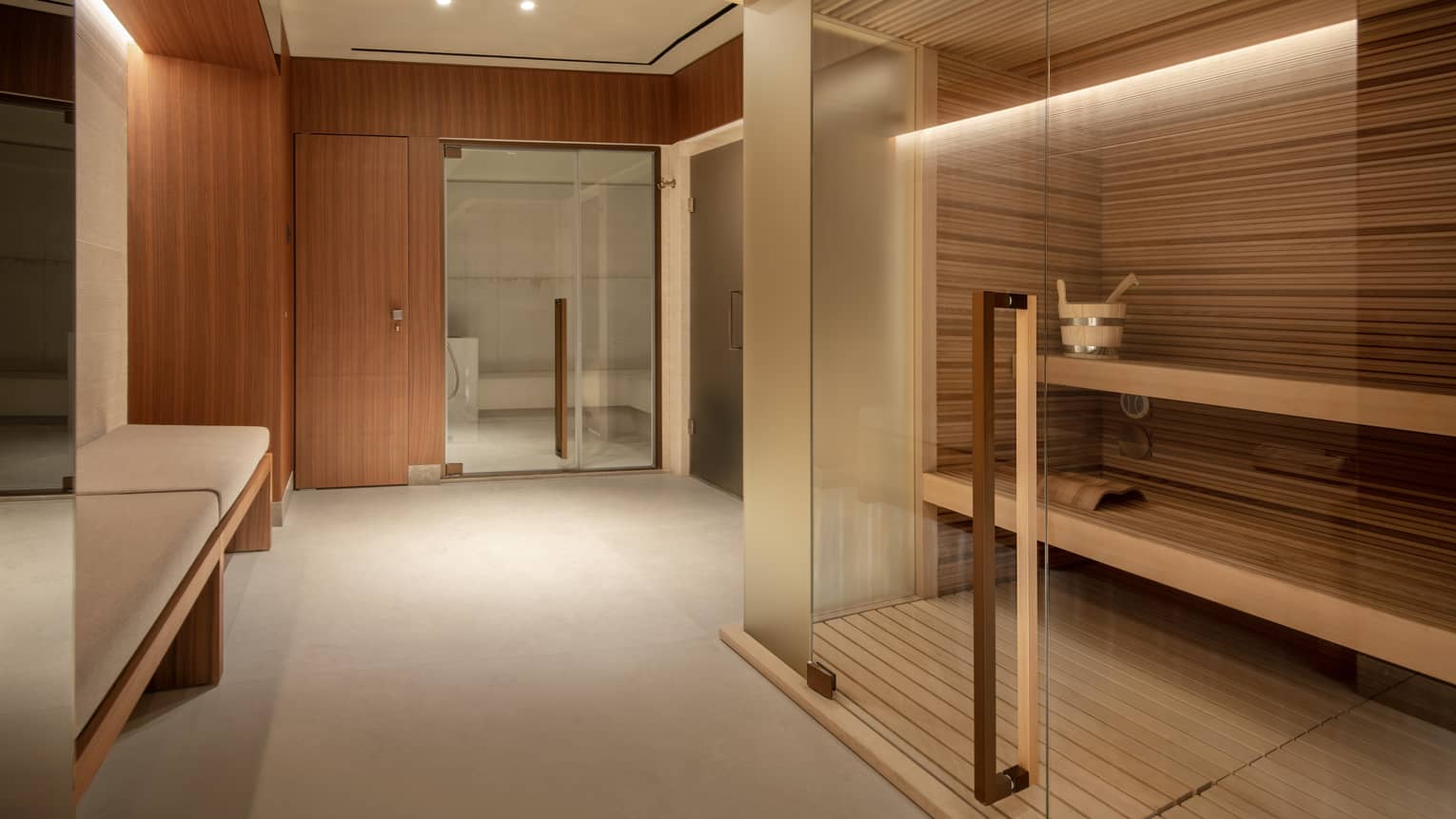 Wood-panelled sauna with benches and glass doors