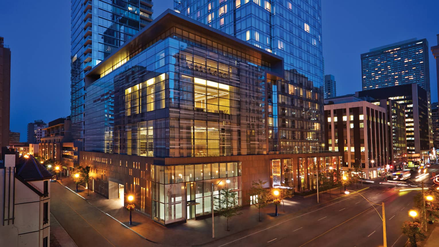 Glass windows lit up at night on Four Seasons Hotel Toronto Yorkville corner building