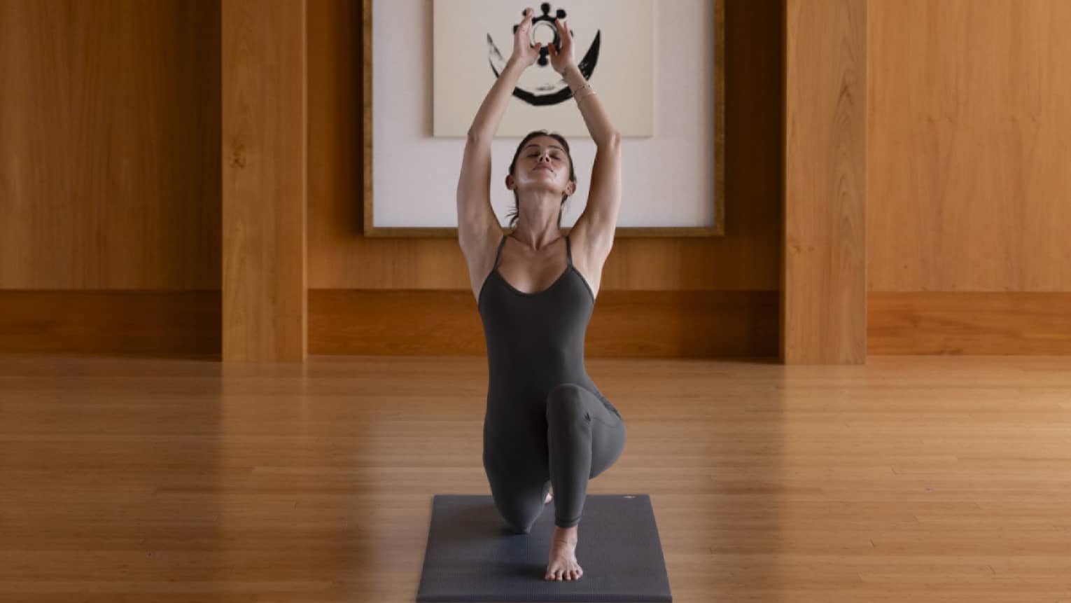 Woman practises yoga in indoor studio with wooden floors and walls