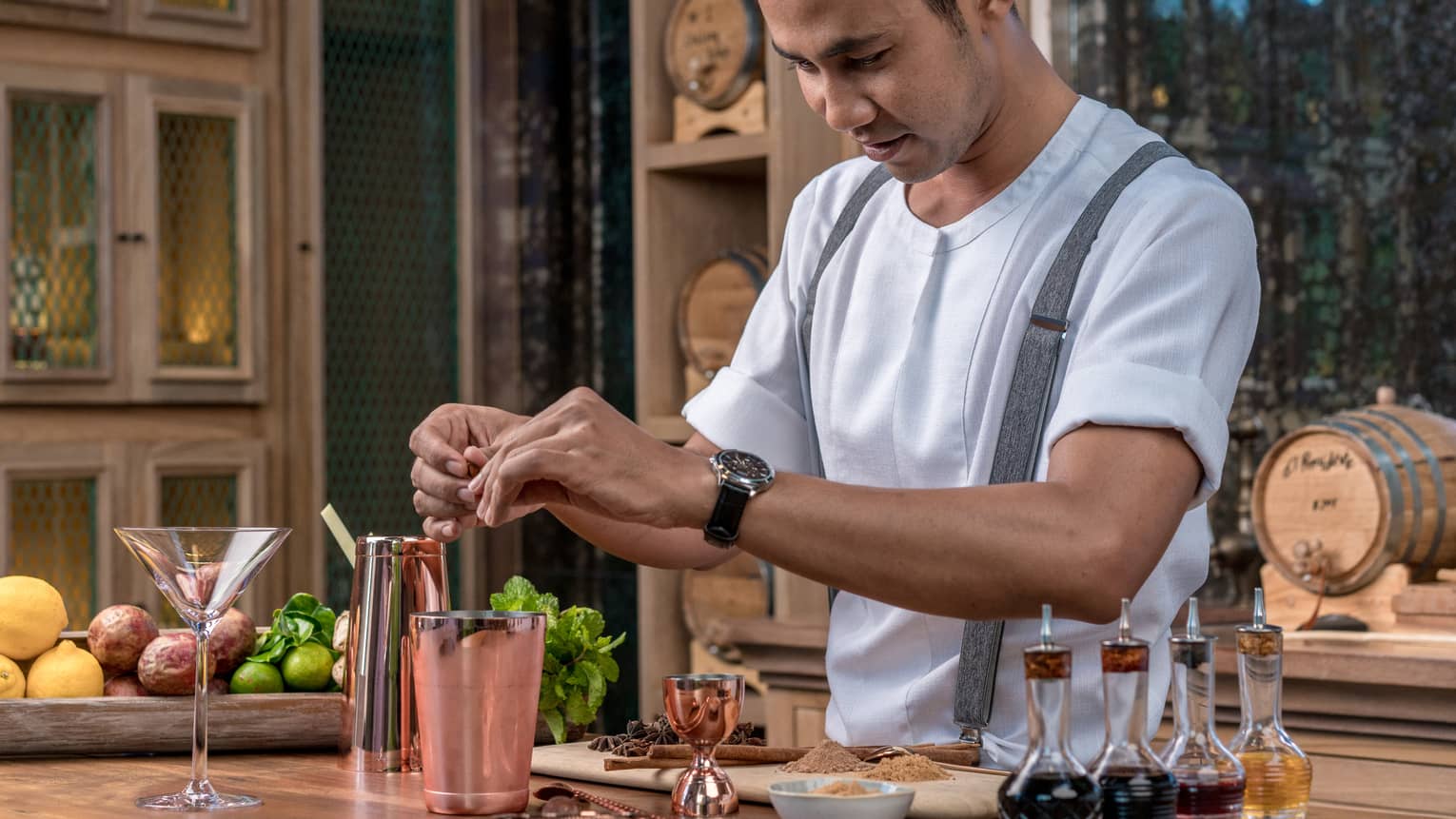 Bartender adds fragrant spices to a copper shaker in preparation for a cocktail 
