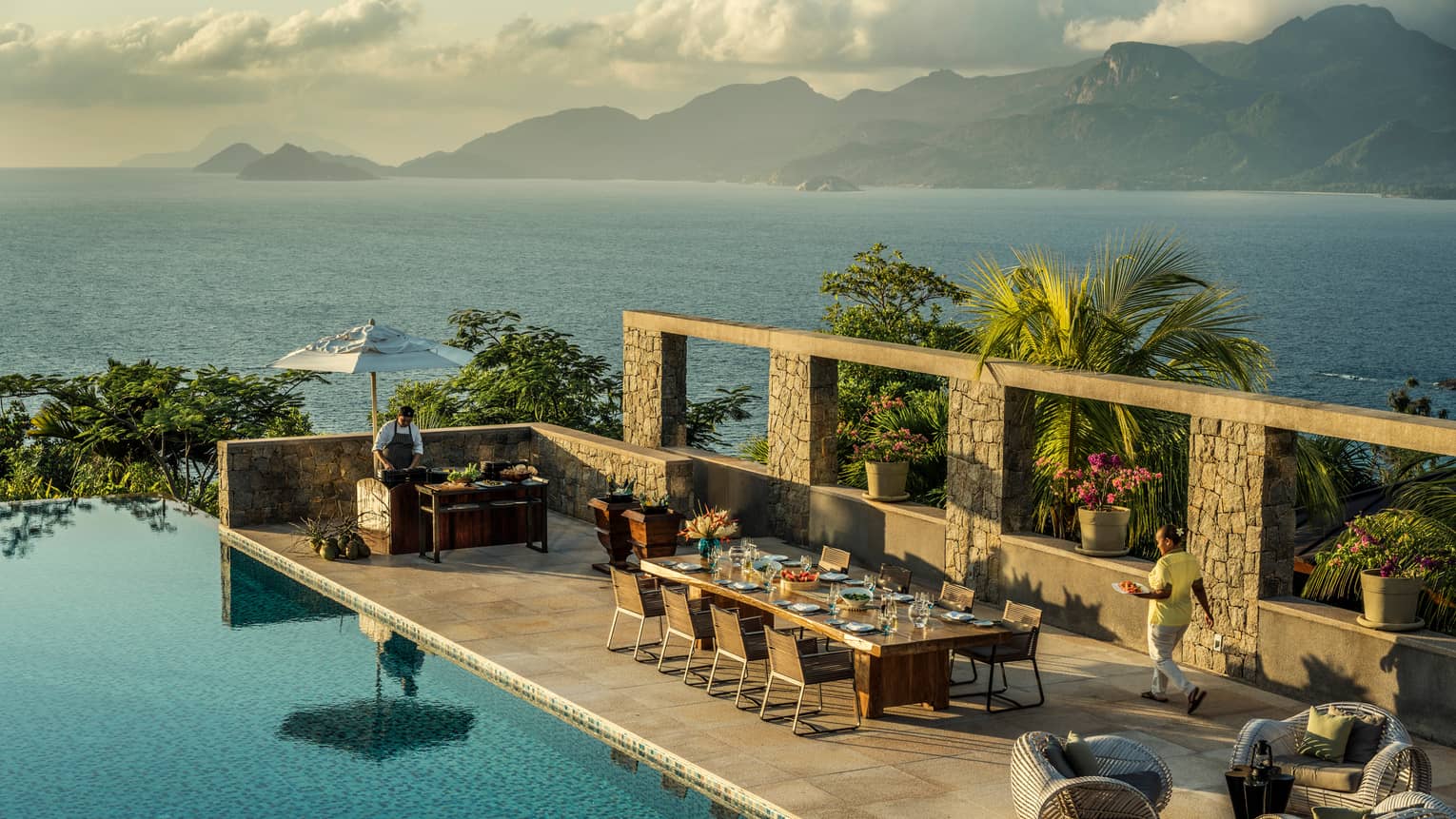 Aerial view of Four-Bedroom Residence Villa private deck with 8-person dining table beside pool, ocean view