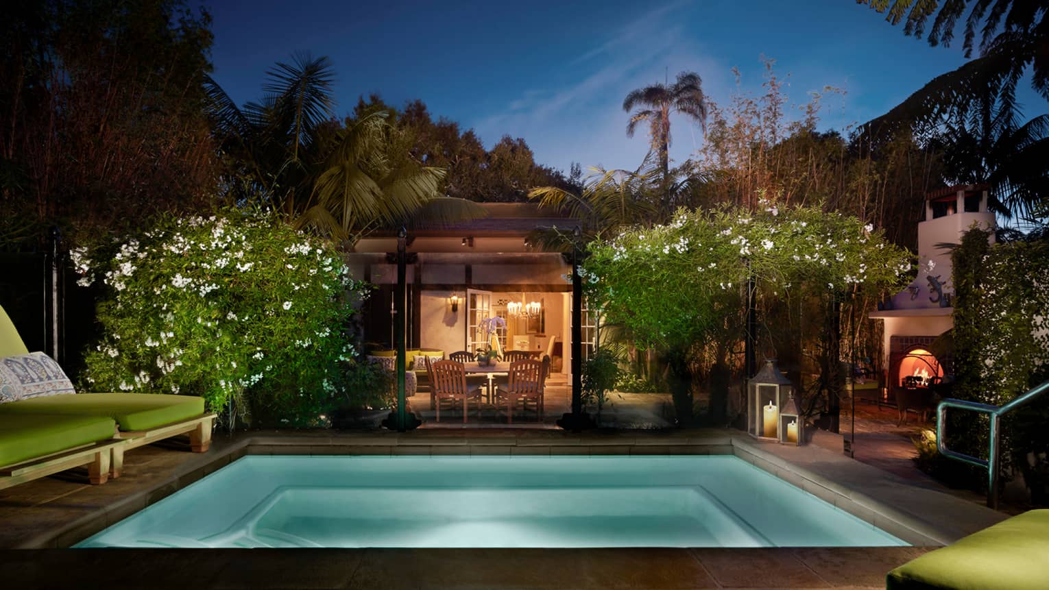 Bungalow Suite backyard at night with illuminated plunge pool, tropical plants, lights from living, dining room
