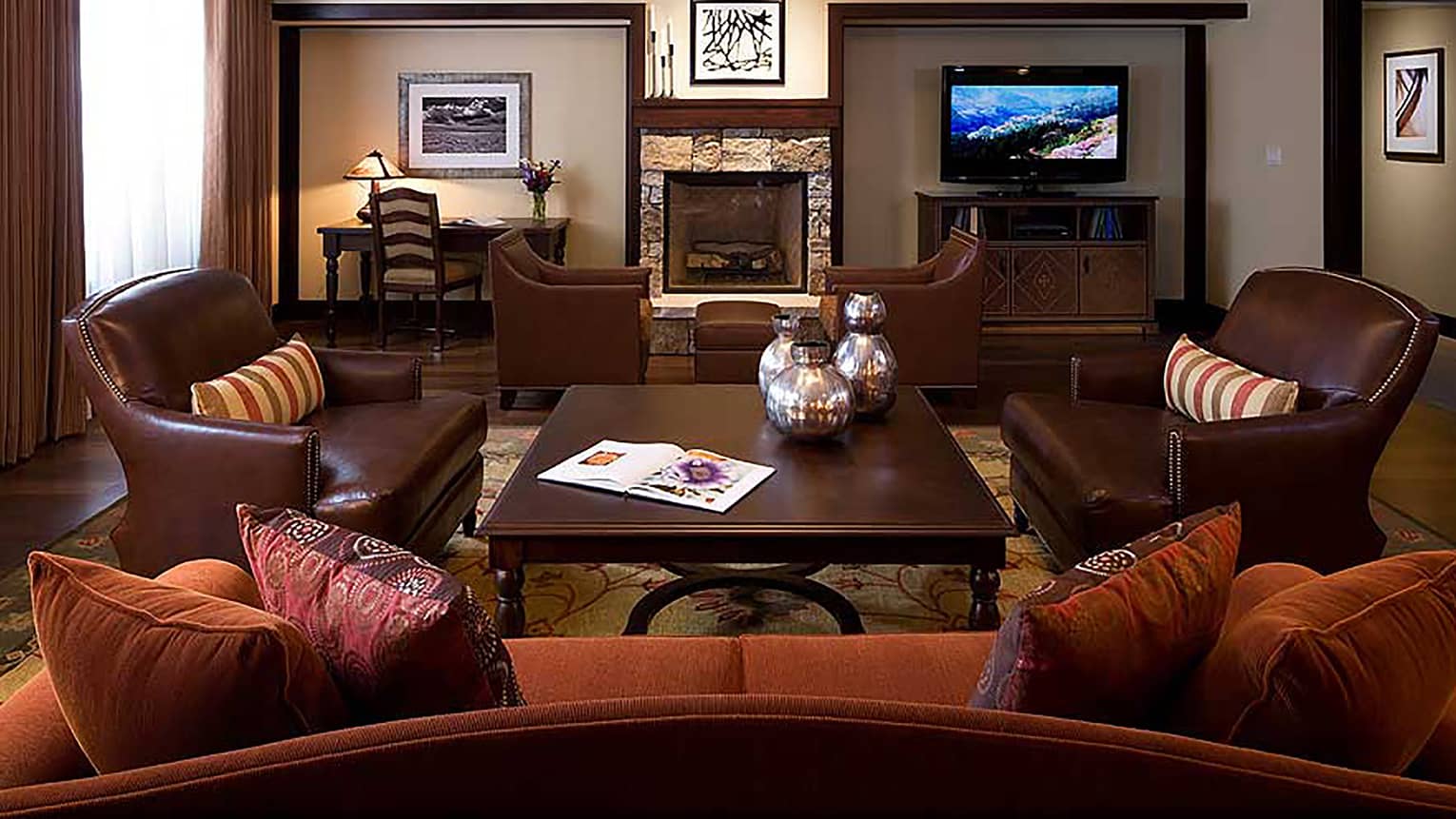 Three-bedroom residence living room with red sofa, leather armchairs, office desk and flat-screen TV