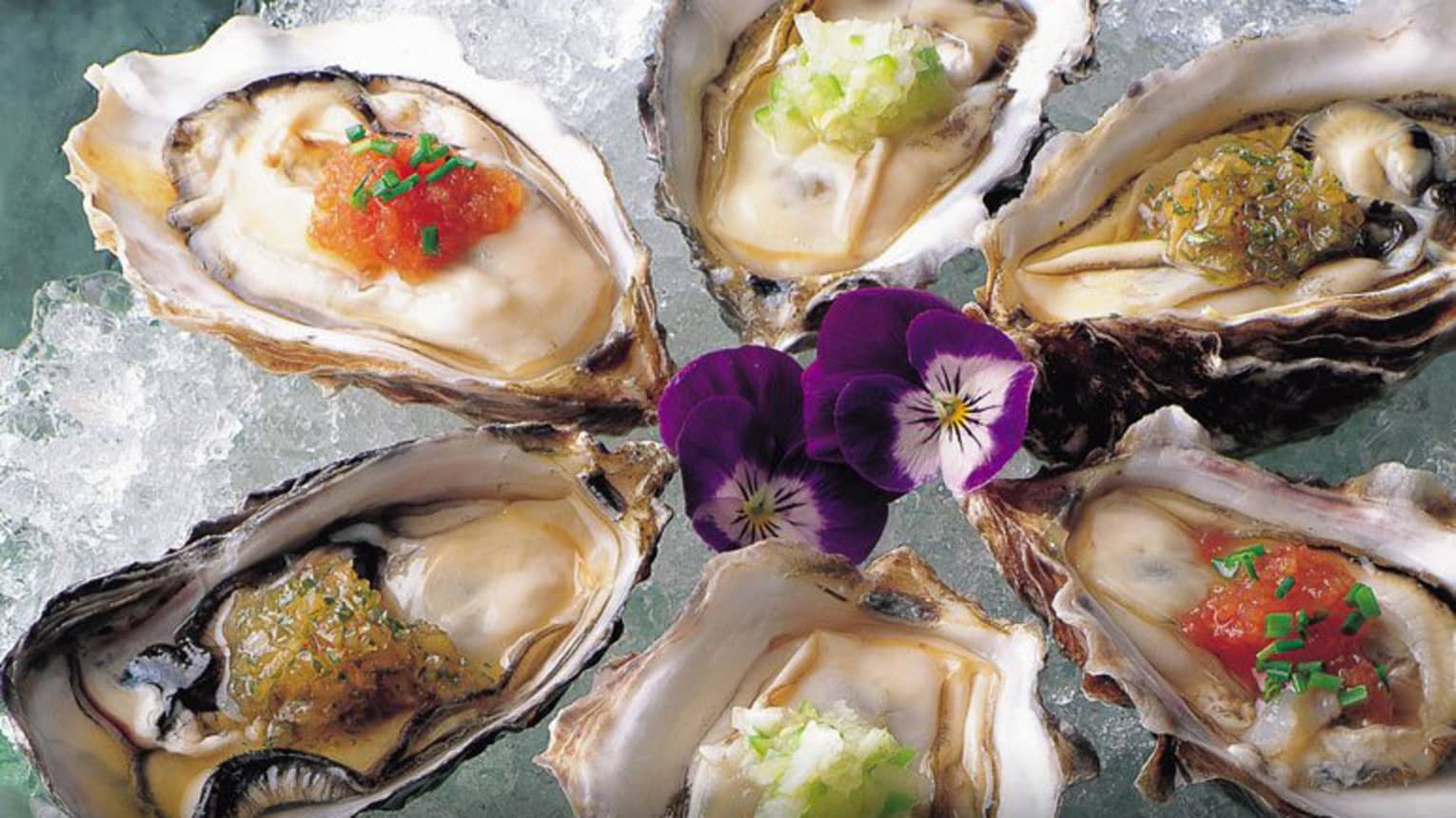 Raw oysters with Nobu Sauces and purple flowers on ice platter