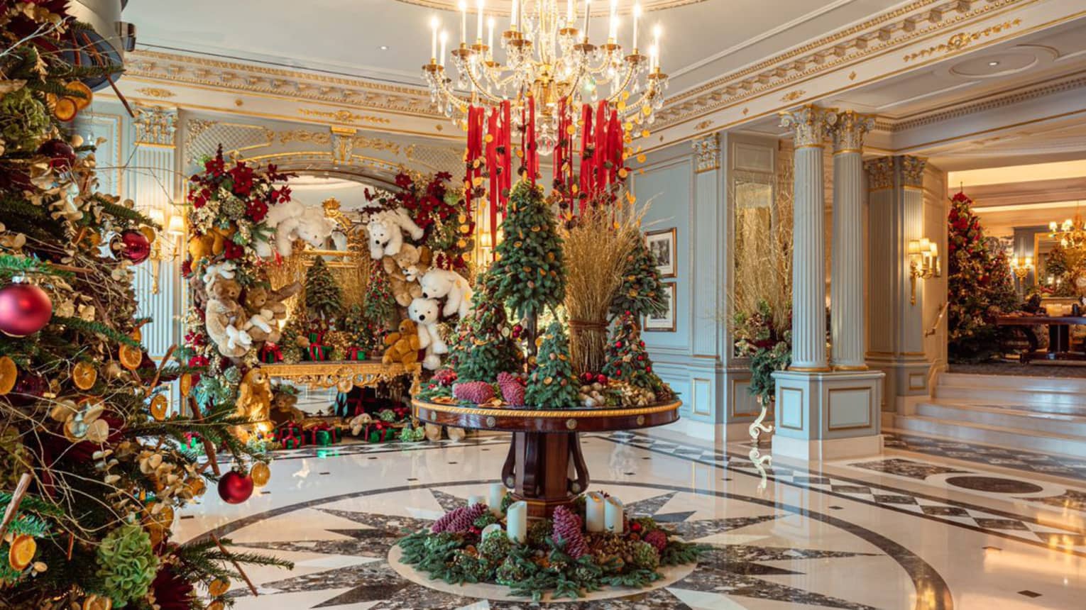 Elegant hotel lobby circular table topped with Christmas tree d�cor under a crystal chandelier