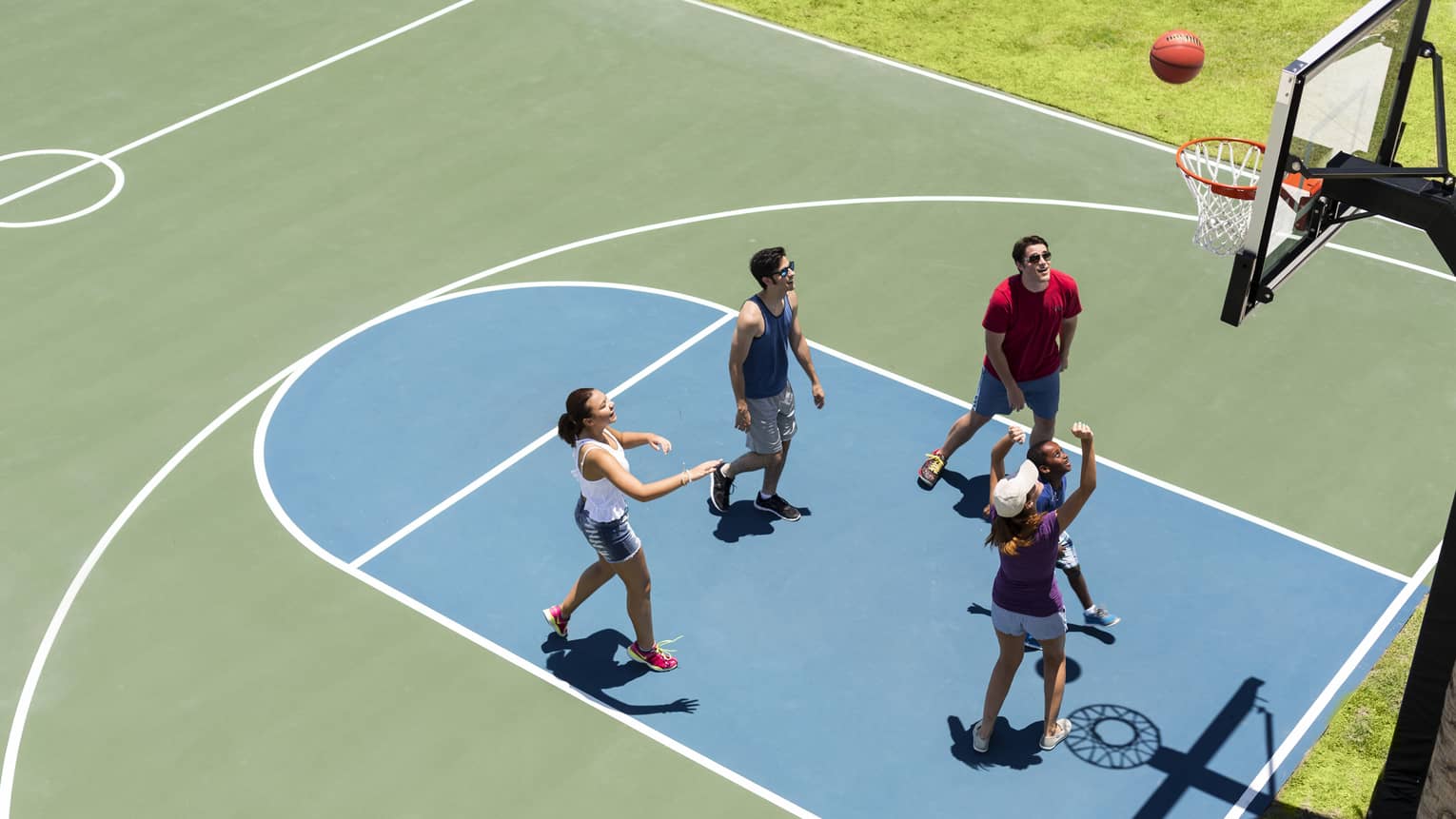 Aerial view of group of friends on basketball court, throwing ball in net