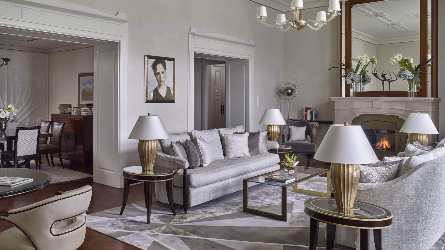 Elegant hotel living room with gray sofas, modern lamps and a fireplace with a large mirror above